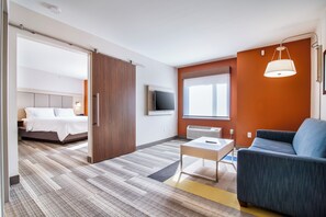 A hotel room with a bed, a desk, a chair, a TV, and a window.