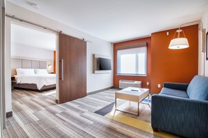 Una habitación de hotel con cama, escritorio, silla, televisor y ventana.