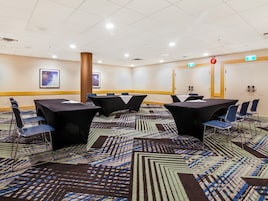 A conference room with tables and chairs, a patterned carpet, and a ceiling with recessed lighting.