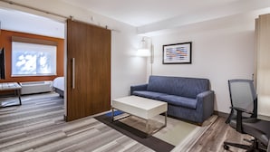 Un espace de bureau moderne avec une armoire en bois, un bureau blanc, un canapé bleu et un fauteuil de bureau noir.