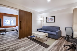 A modern office space with a wooden wardrobe, a white desk, a blue sofa, and a black office chair.