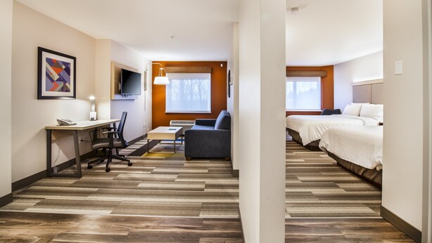 Une chambre d’hôtel équipée d’un bureau, d’une chaise, d’un canapé et de deux lits.