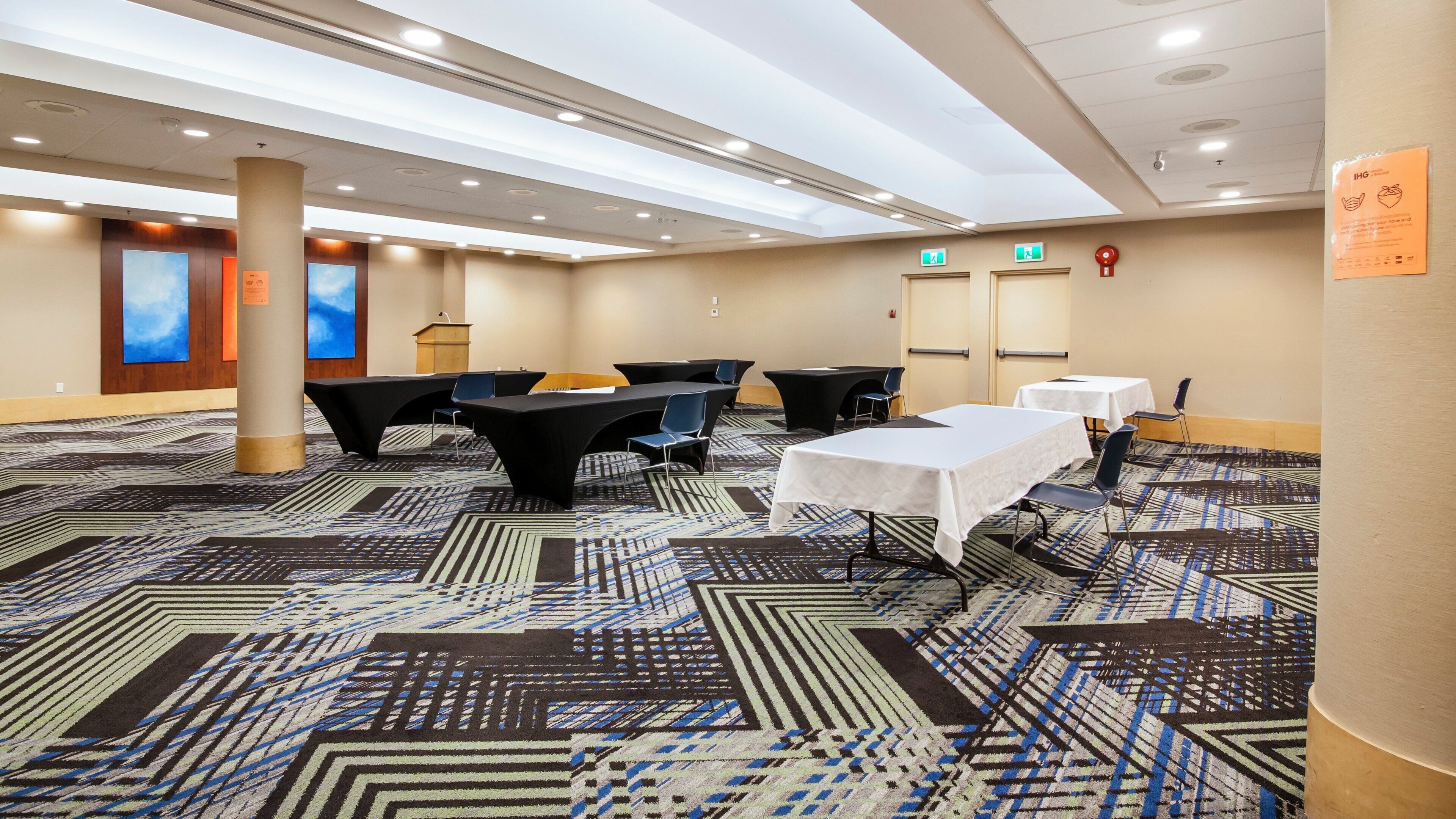 Un salón de conferencias con mesas, sillas y un atril.
