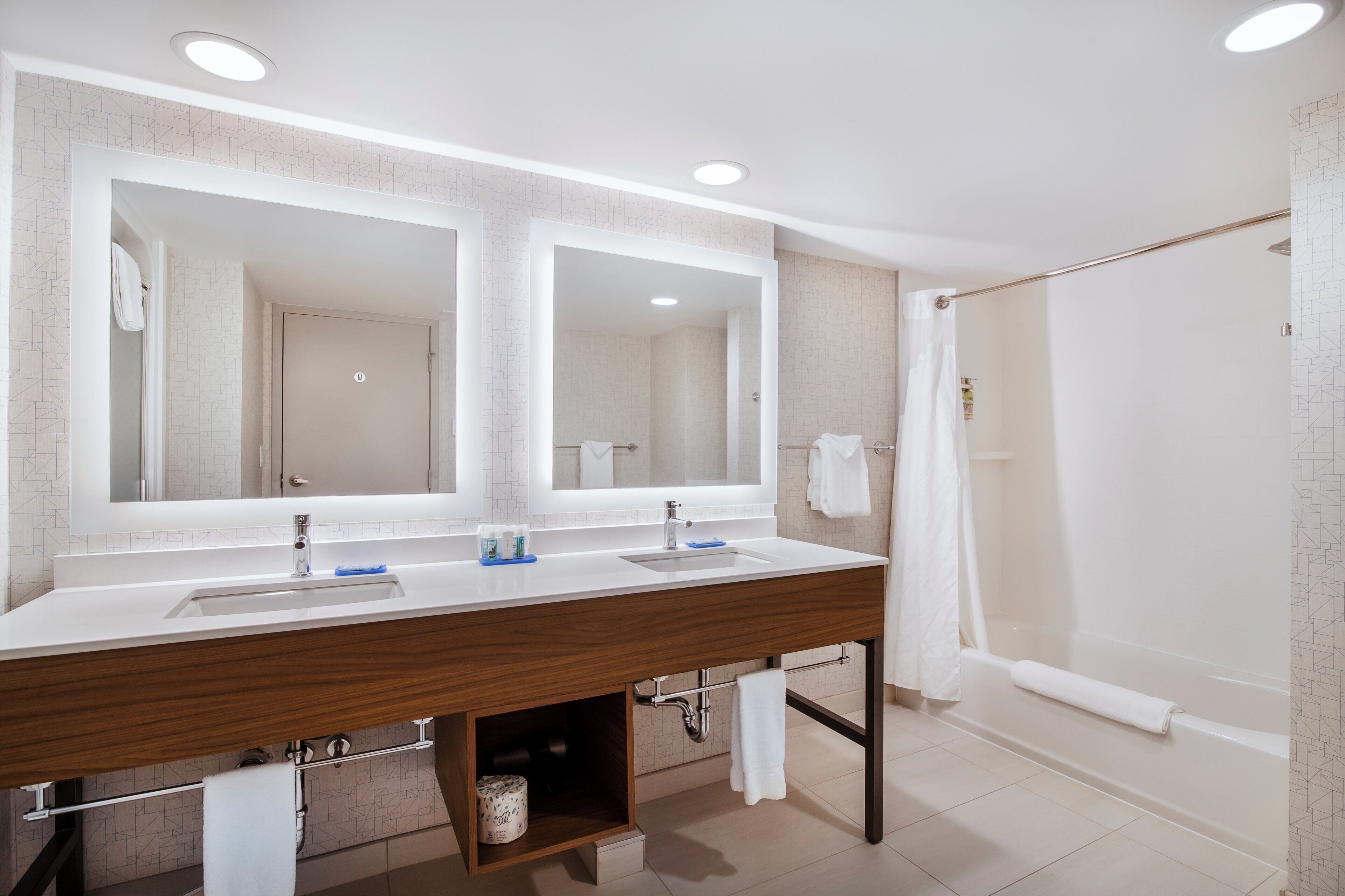 Casa de banho moderna com duas pias, um espelho grande e zona de duche.