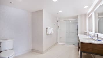 Un baño moderno con inodoro, ducha y tocador con espejo.