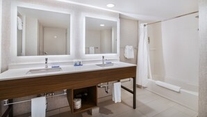 Une salle de bain moderne avec un double lavabo, de grands miroirs, une douche et un porte-serviettes.