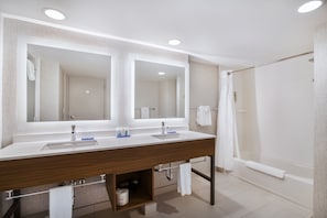 A modern bathroom with a double sink, large mirrors, a shower, and a towel rack.