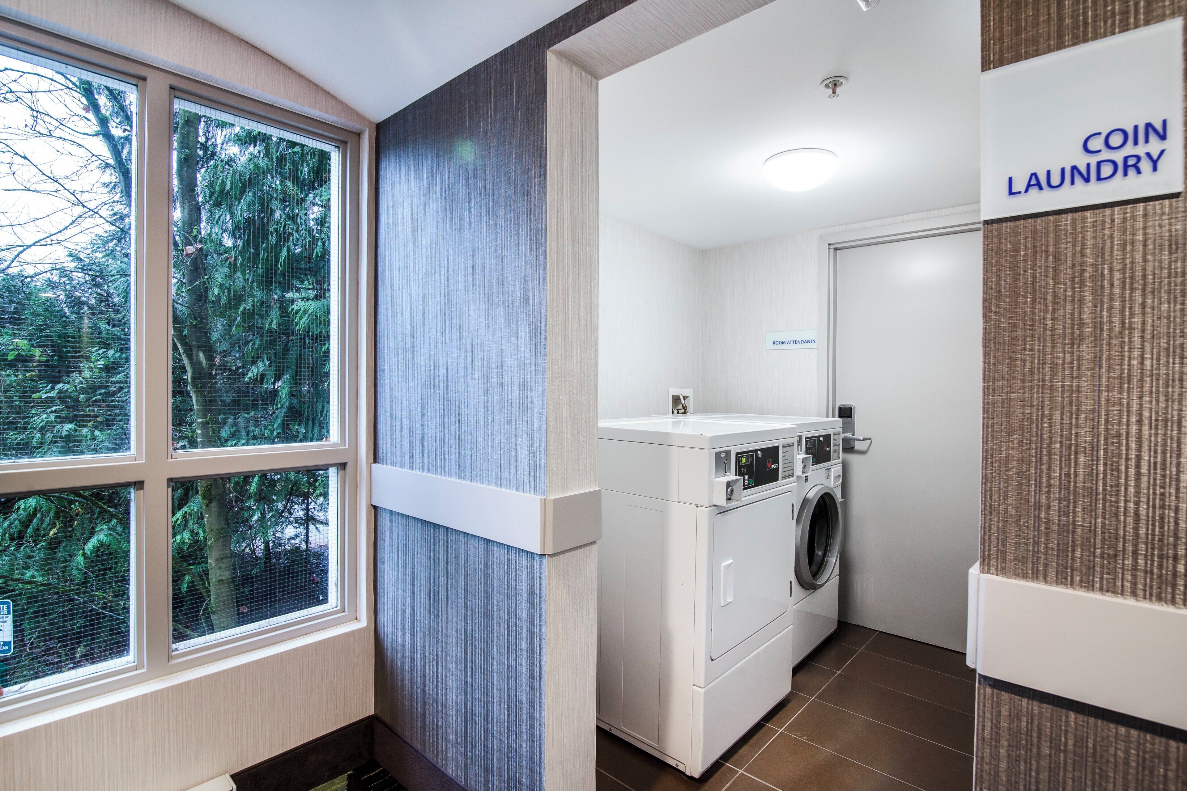 A laundry area with a washing machine and a sign that reads 'COIN LAUNDRY'.