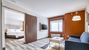 Une chambre d’hôtel avec un lit, un canapé, une télévision et une fenêtre.