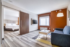 A hotel room with a bed, a sofa, a TV, and a window.