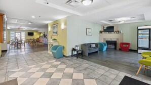 A spacious lobby with a checkered floor, seating areas, a fireplace, and a TV mounted on the wall.