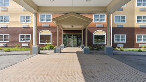 A hotel entrance with a covered walkway, a central door, and a brick-paved area.