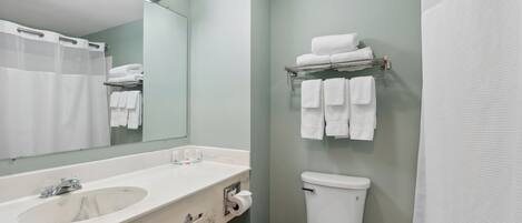 Un baño con lavabo, espejo, inodoro, toallero y cortina de ducha.