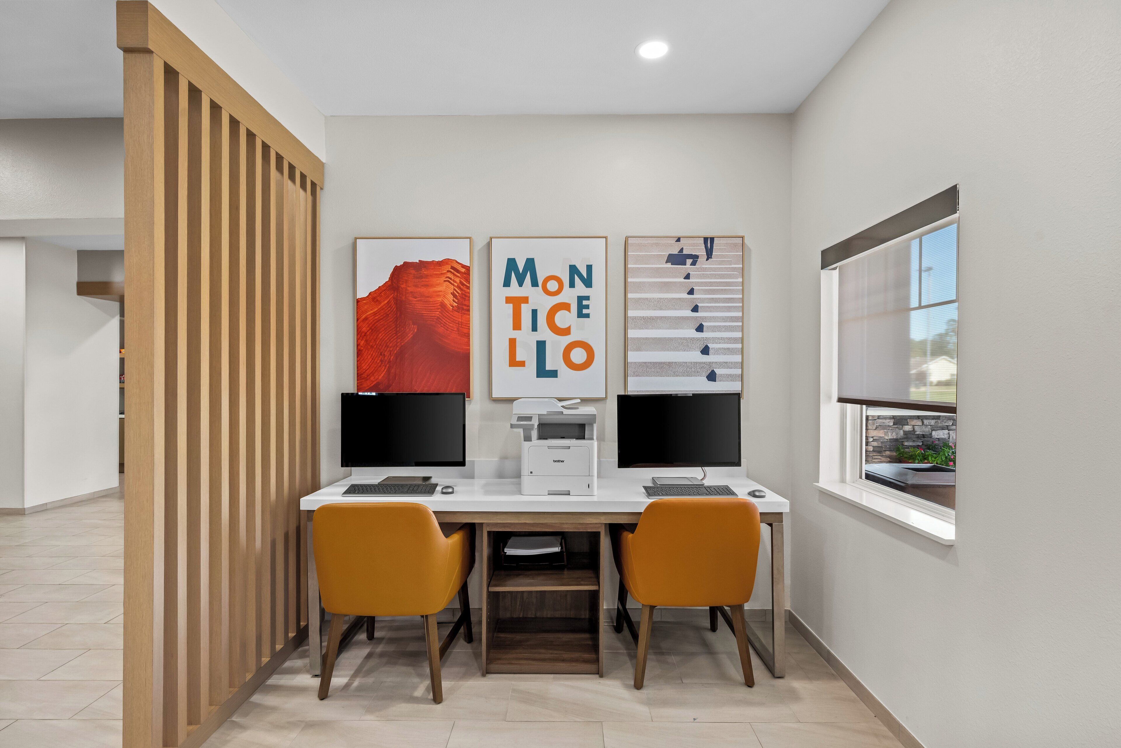 Un espacio de oficina moderno con dos escritorios, dos sillas y tres monitores.