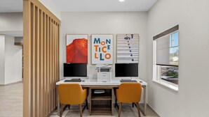 A modern office space with two desks, two chairs, and three monitors. - Holiday Inn Express Monticello by IHG (Monticello)