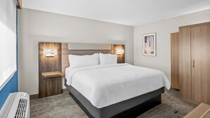 A hotel room with a large bed, wooden headboard, bedside tables with lamps, a wardrobe, and a wall-mounted artwork. - Holiday Inn Express Monticello by IHG (Monticello)