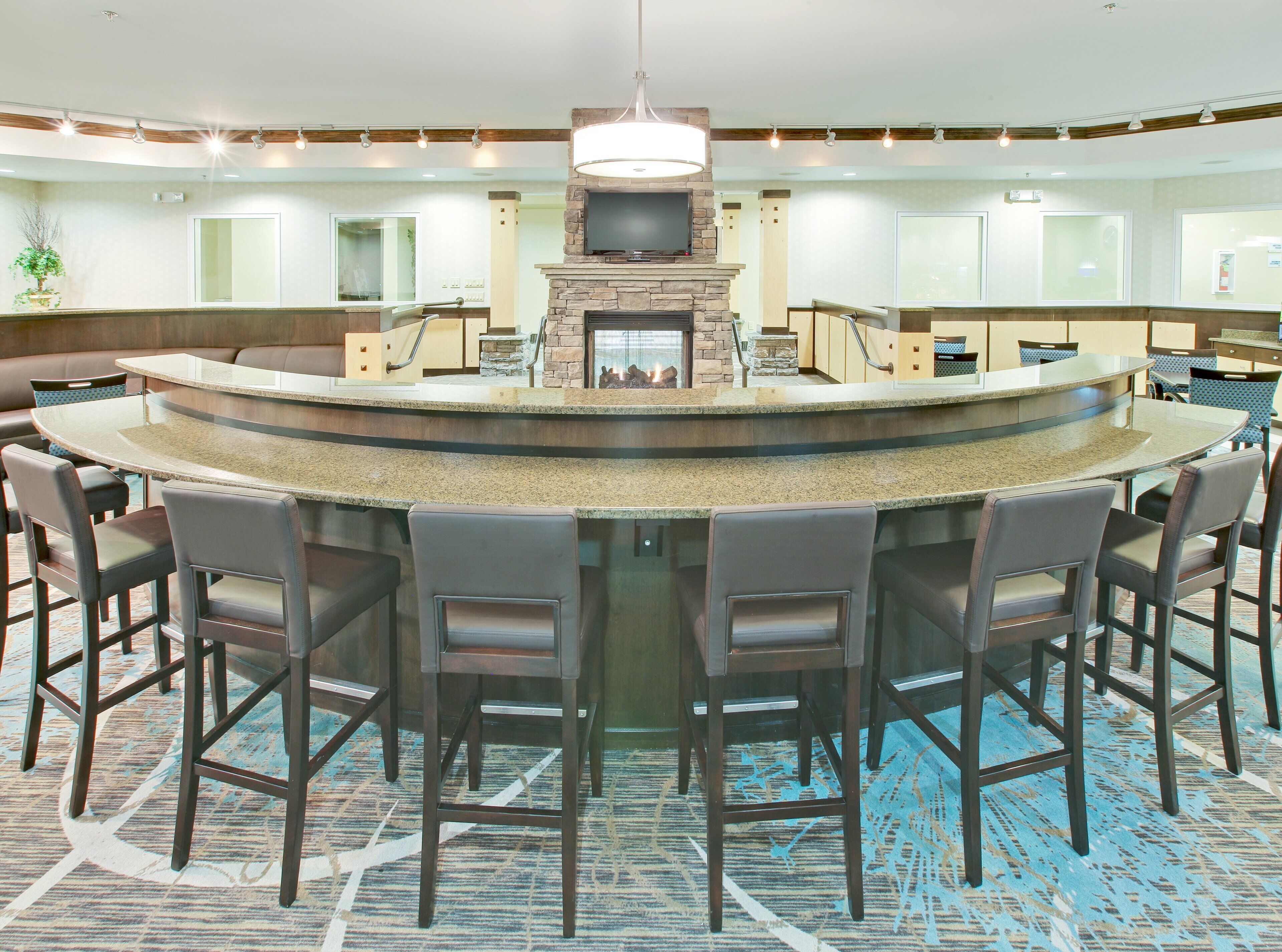 A bar area with a stone fireplace, multiple bar stools, and a large mirror above the counter.