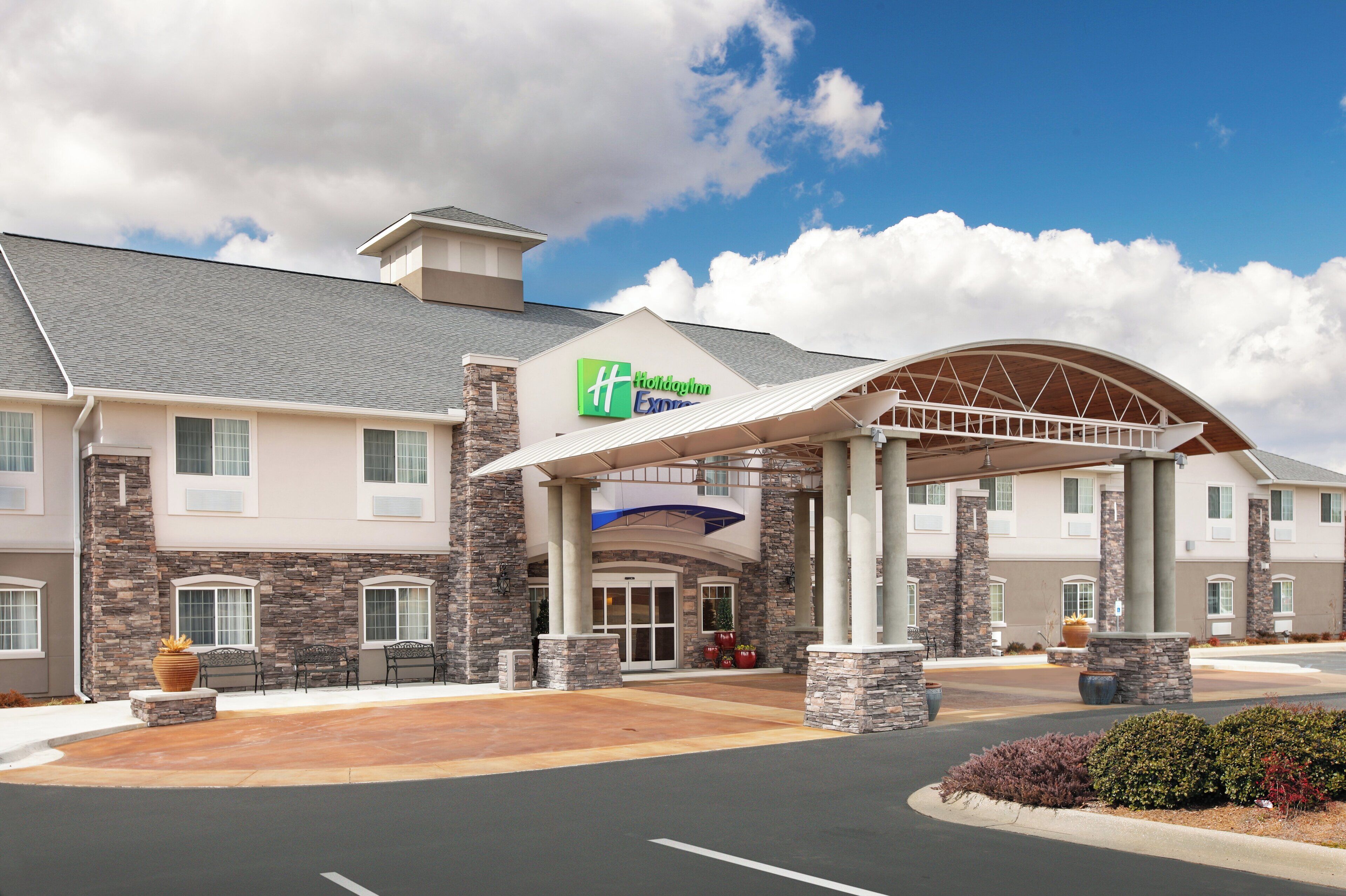 A Holiday Inn Express hotel with a covered entrance, stone facade, and a parking lot.