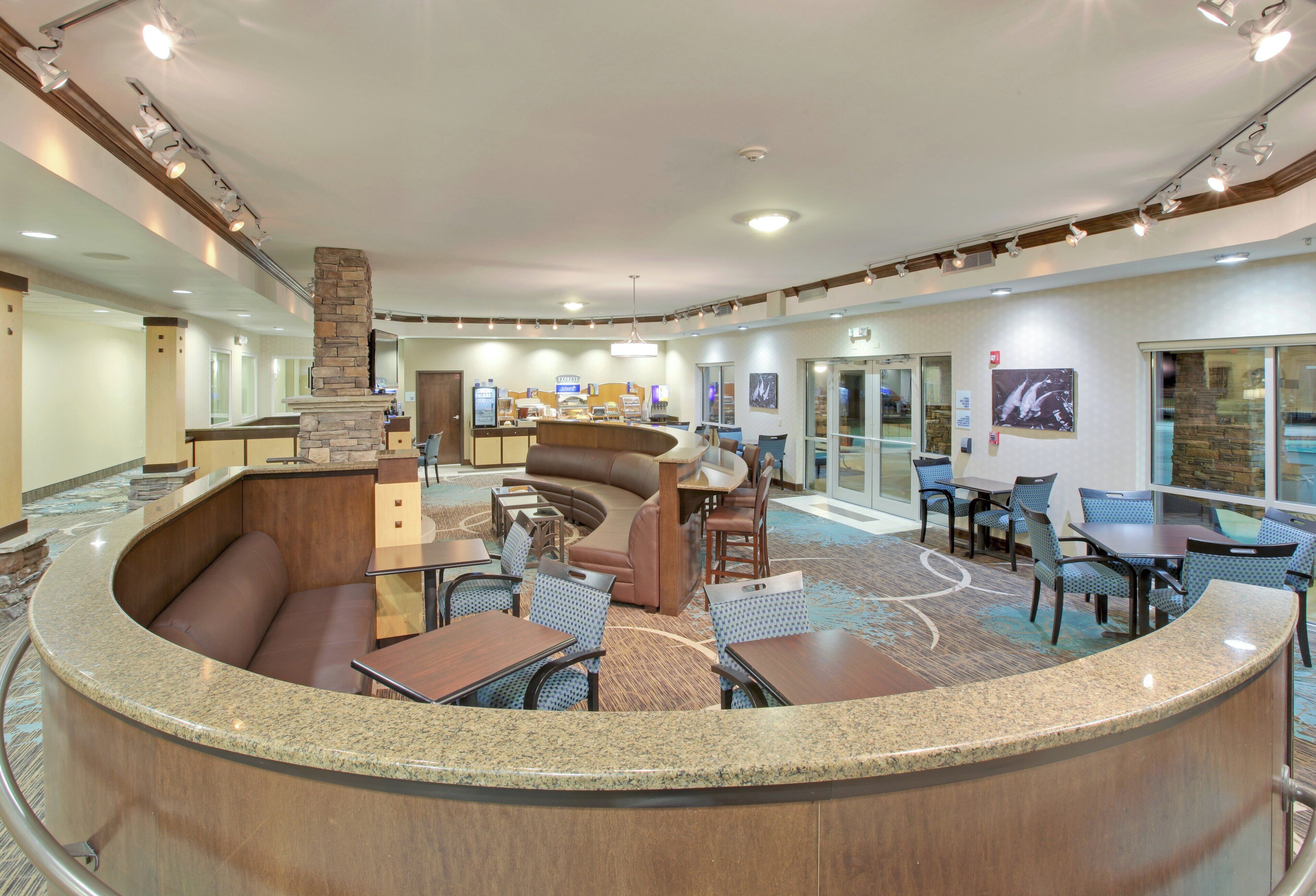 A hotel lobby with a curved reception desk, seating area with couches and tables, and a large window with a view.
