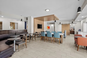 A modern dining area with a mix of seating options including a long communal table and individual chairs, a sofa, and small round tables. - Holiday Inn Express Monticello by IHG (Monticello)