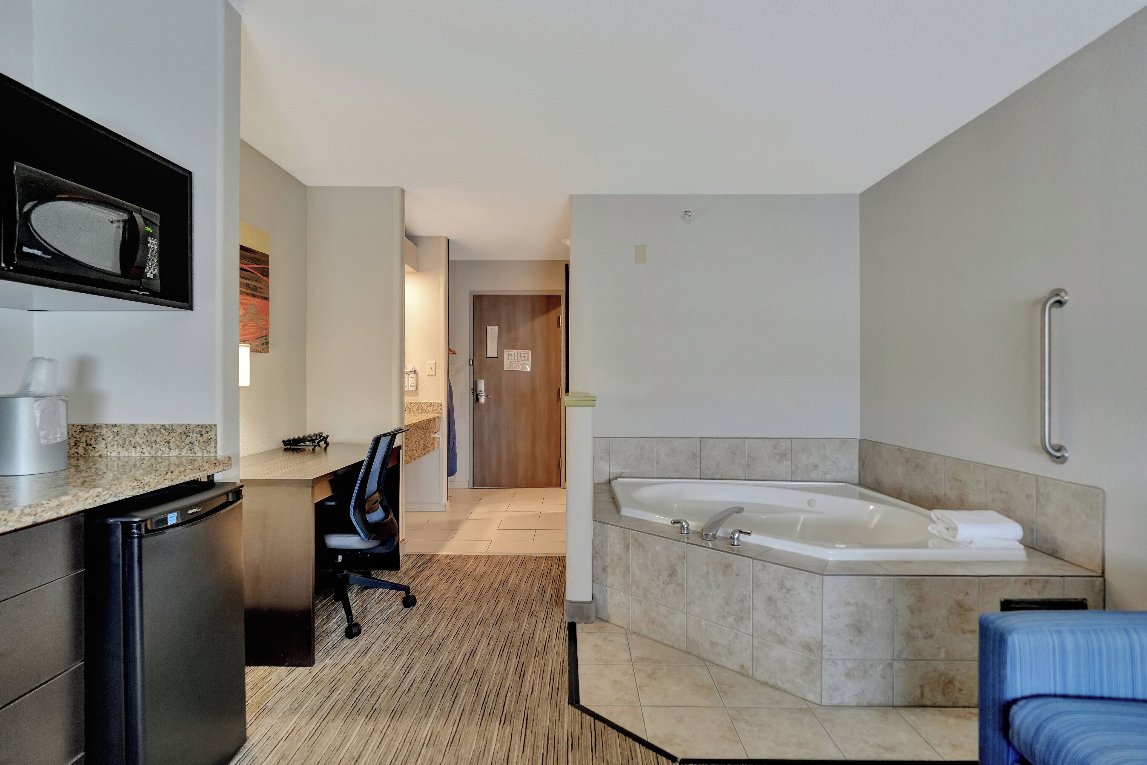 Une salle de bain d’hôtel moderne, dotée d’une grande baignoire, d’un four à micro-ondes et d’une petite kitchenette.