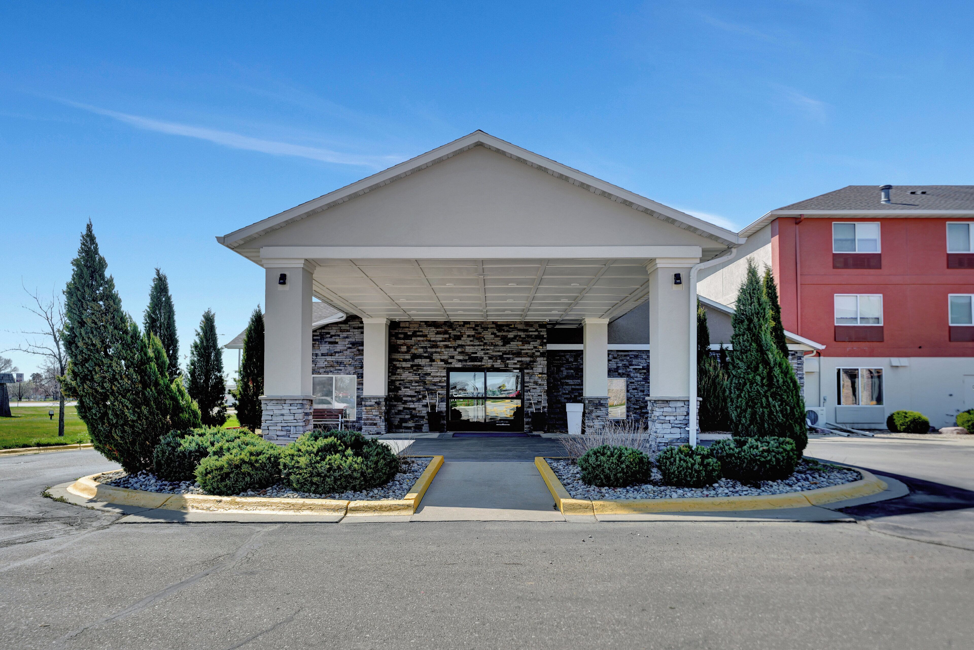 A building with a stone facade, a covered entrance, and a parking lot.