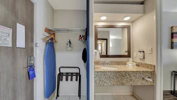 A bathroom with a granite countertop, a sink, a mirror, and a towel rack.