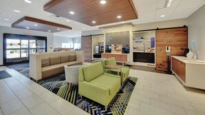 A modern lobby with seating areas, a coffee station, and a reception desk.