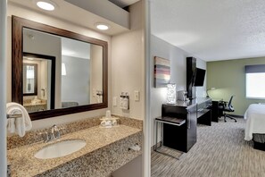 Une salle de bain d’hôtel avec un lavabo doté d’un plan de travail en granit, un grand miroir et un porte-serviettes.