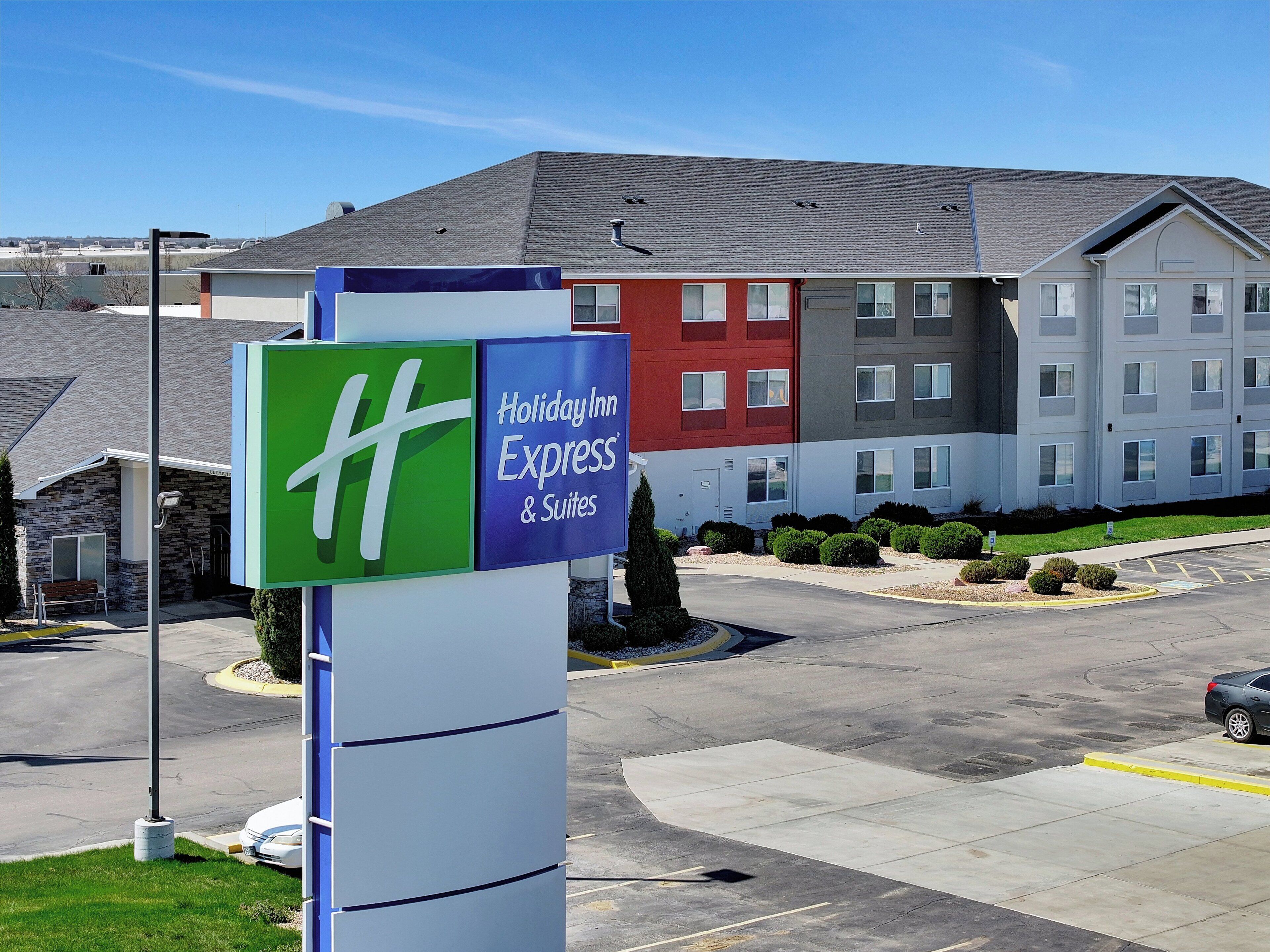 Señal de Holiday Inn Express & Suites con un edificio moderno al fondo.