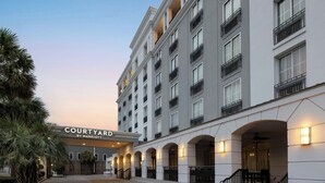 A Courtyard by Marriott hotel with a modern facade, multiple balconies, and a well-lit entrance. - Courtyard Charleston Historic District (Charleston)