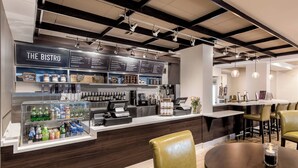 A modern bistro with a counter displaying various beverages and a menu. There are leather chairs and a round table in the seating area. - Courtyard Charleston Historic District (Charleston)