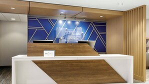 Una reception dal design moderno, con un elemento in legno e una parete blu geometrica alle spalle.