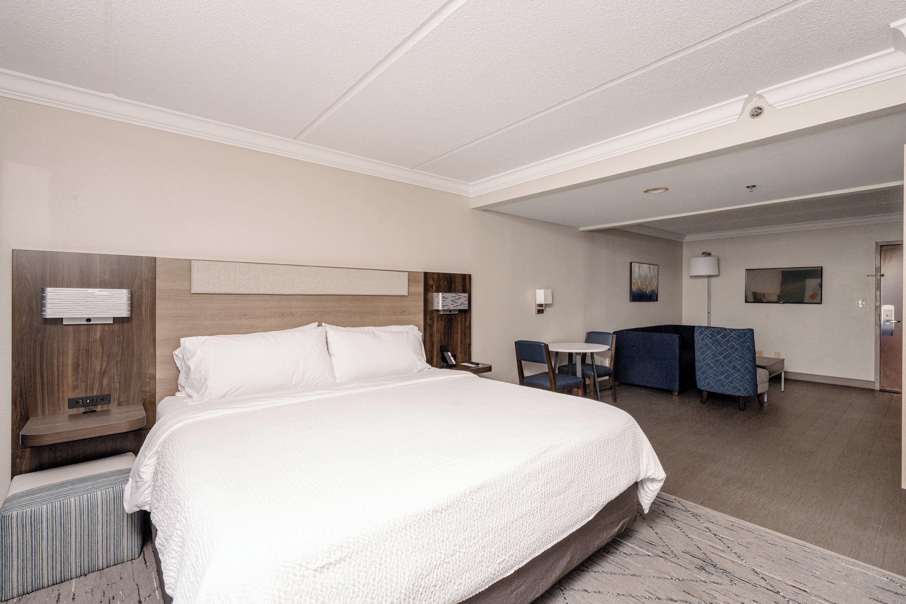 A hotel room with a large bed, a desk, a chair, a small table, and a couch.