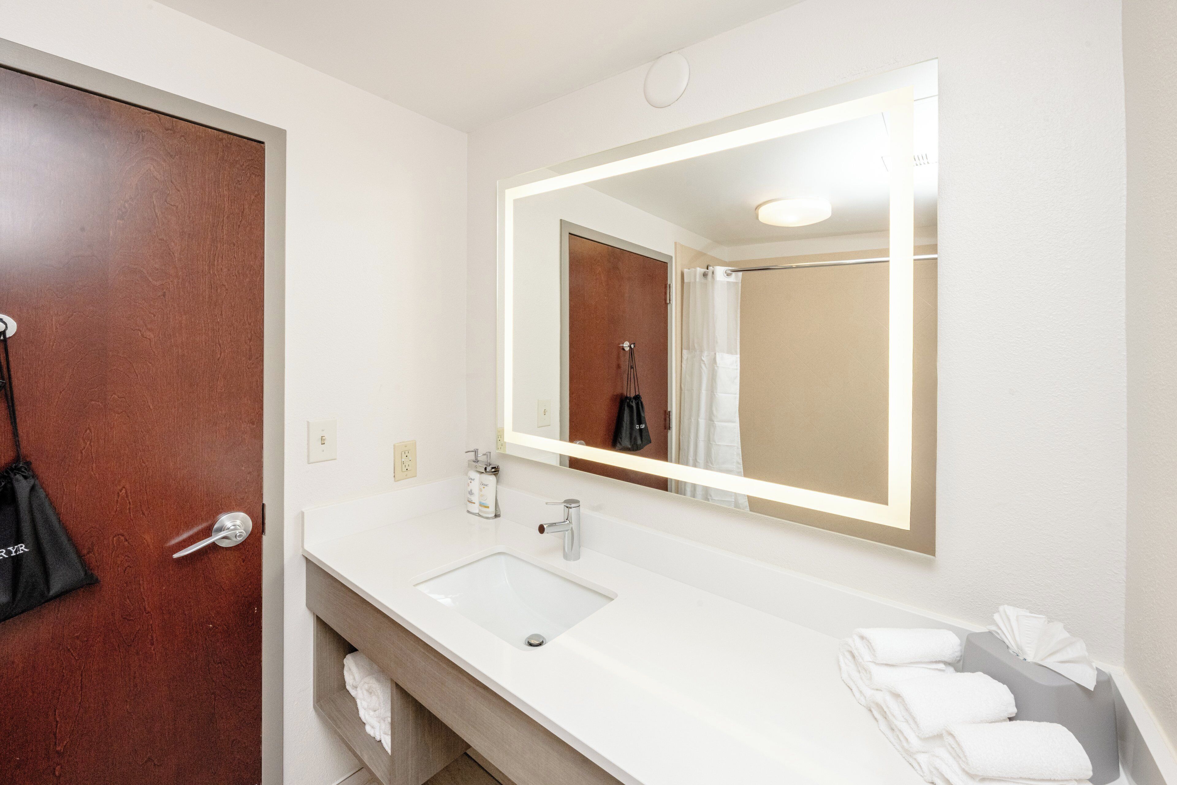A bathroom with a white sink, a large mirror, and a towel rack.