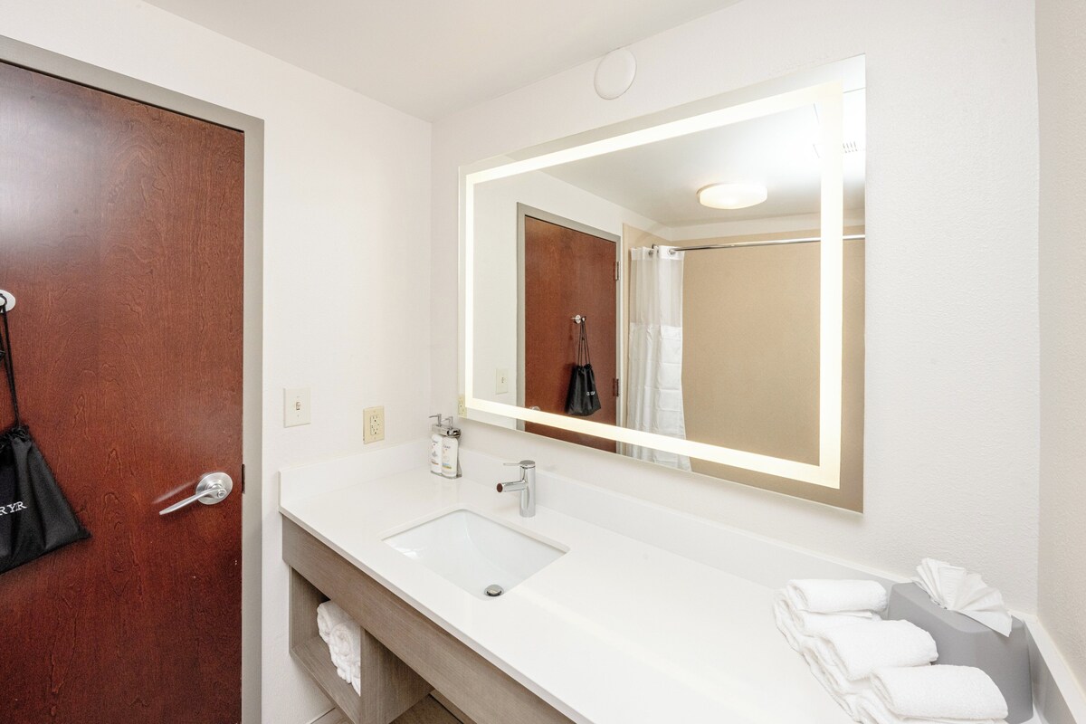 A bathroom with a white sink, a large mirror, and a towel rack.