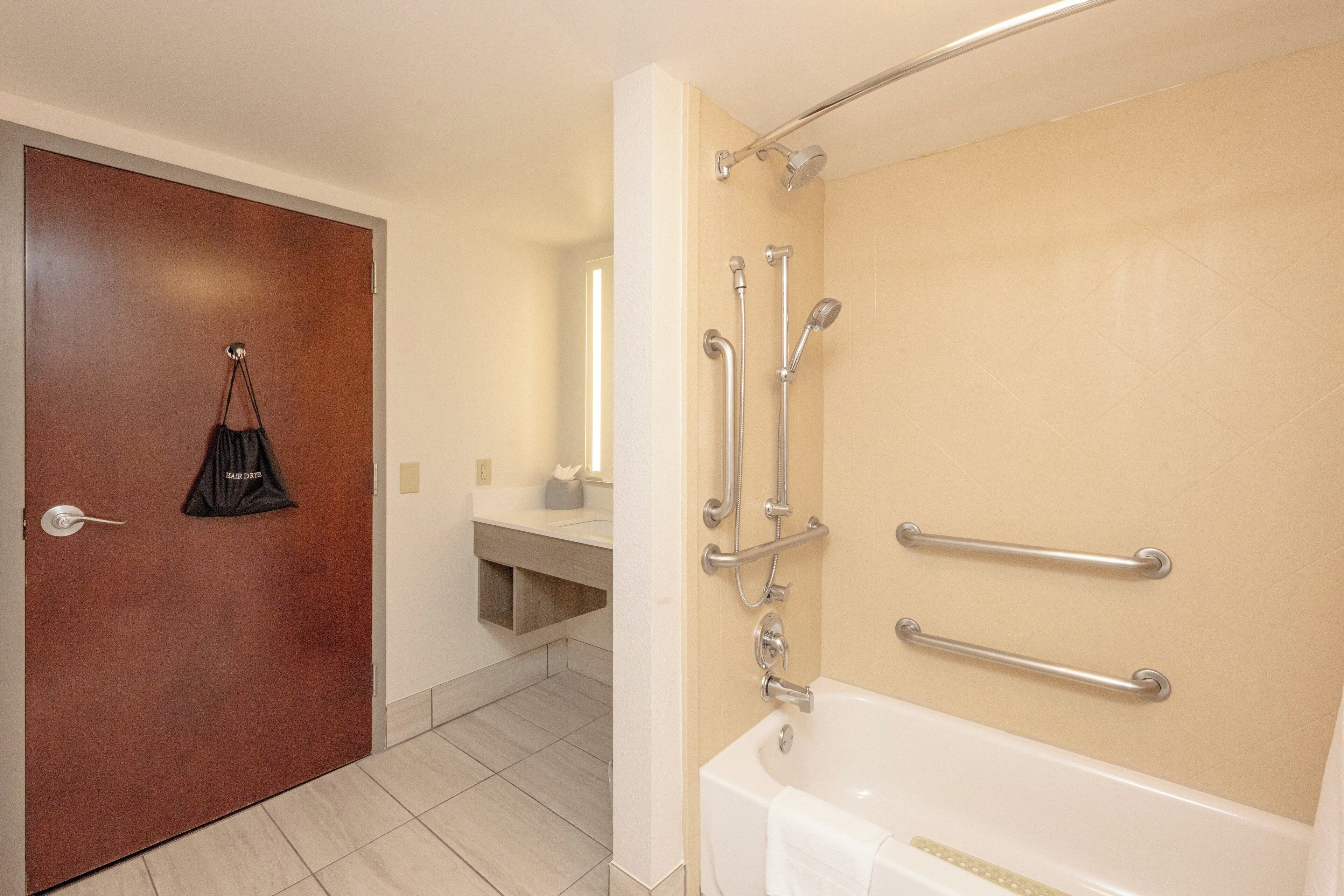 Un baño con bañera, ducha y barras de apoyo.
