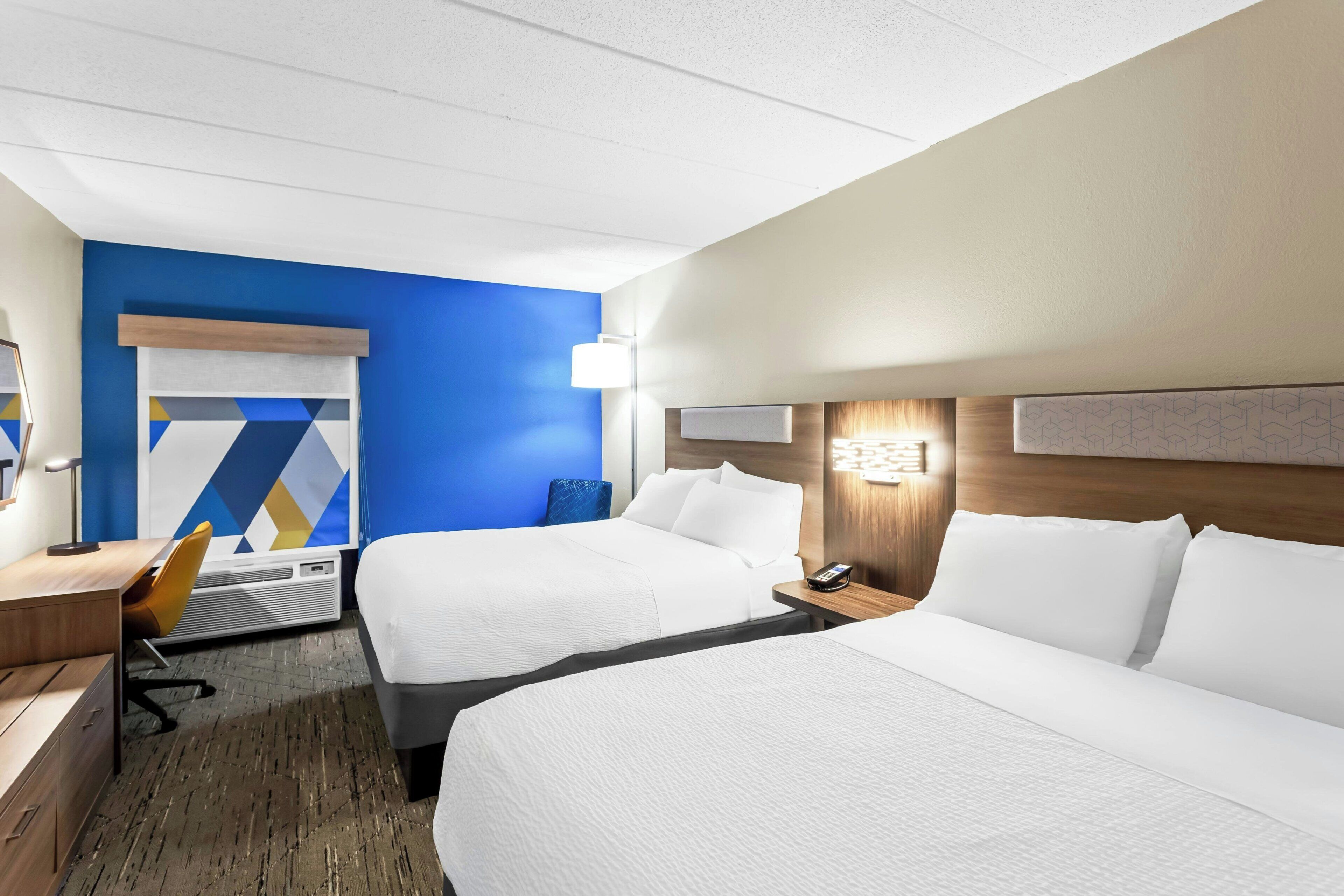 Ein Hotelzimmer mit zwei Betten, einem Schreibtisch, einem Stuhl und einer Wandleuchte.