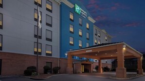 A Holiday Inn Express hotel with a covered entrance, brick facade, and a sign indicating the name and suite availability. - Holiday Inn Express Suites Charleston by IHG (Charleston)