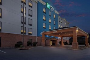 A Holiday Inn Express hotel with a covered entrance, brick facade, and a sign indicating the name and suite availability.
