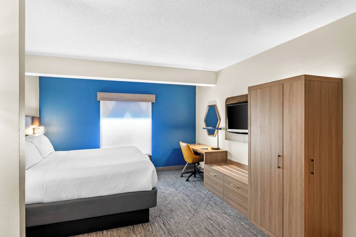 Une chambre d’hôtel comprenant un lit, un bureau, une chaise, une armoire et un téléviseur.
