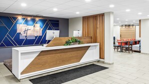 A reception desk with a modern design, a seating area with tables and chairs, and a wall with geometric patterns. - Holiday Inn Express Suites Charleston by IHG (Charleston)