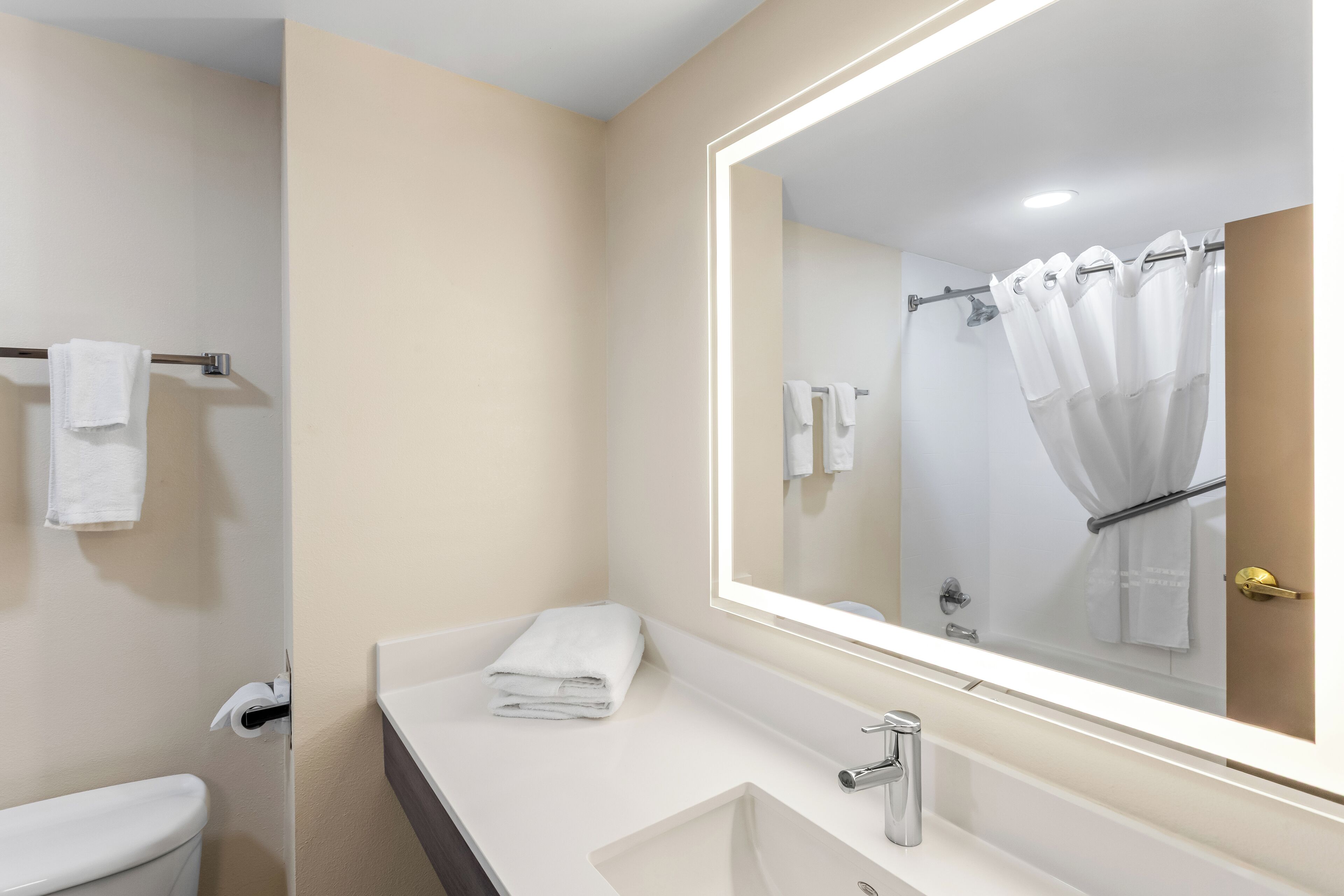 A modern bathroom with a white sink, a large mirror, and a shower curtain.