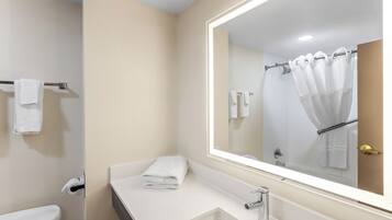 A modern bathroom with a white sink, a large mirror, and a shower curtain.