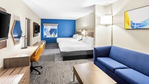 A hotel room with a bed, a desk, a chair, a sofa, and a TV.