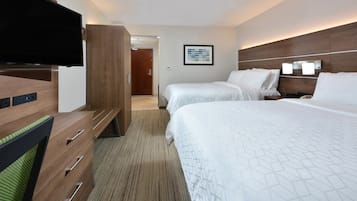 Habitación de hotel con dos camas, un televisor, un aparador de madera y un cuadro en la pared.