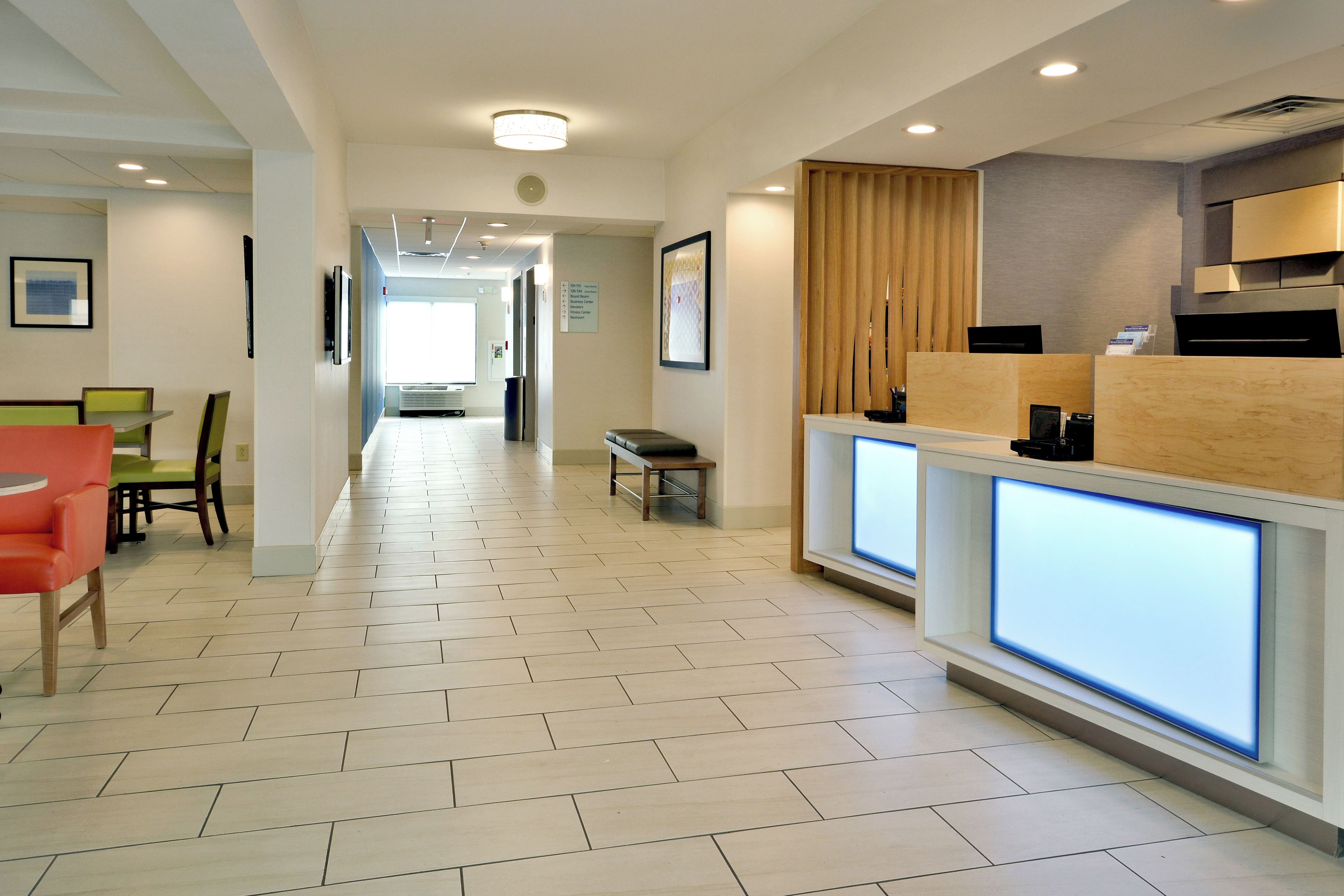 A hotel lobby with a reception desk, seating area, and a hallway leading to other rooms.