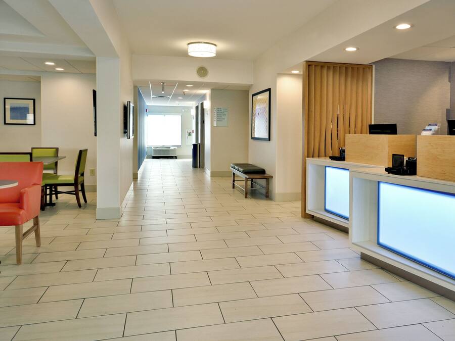 A hotel lobby with a reception desk, seating area, and a hallway leading to other rooms.