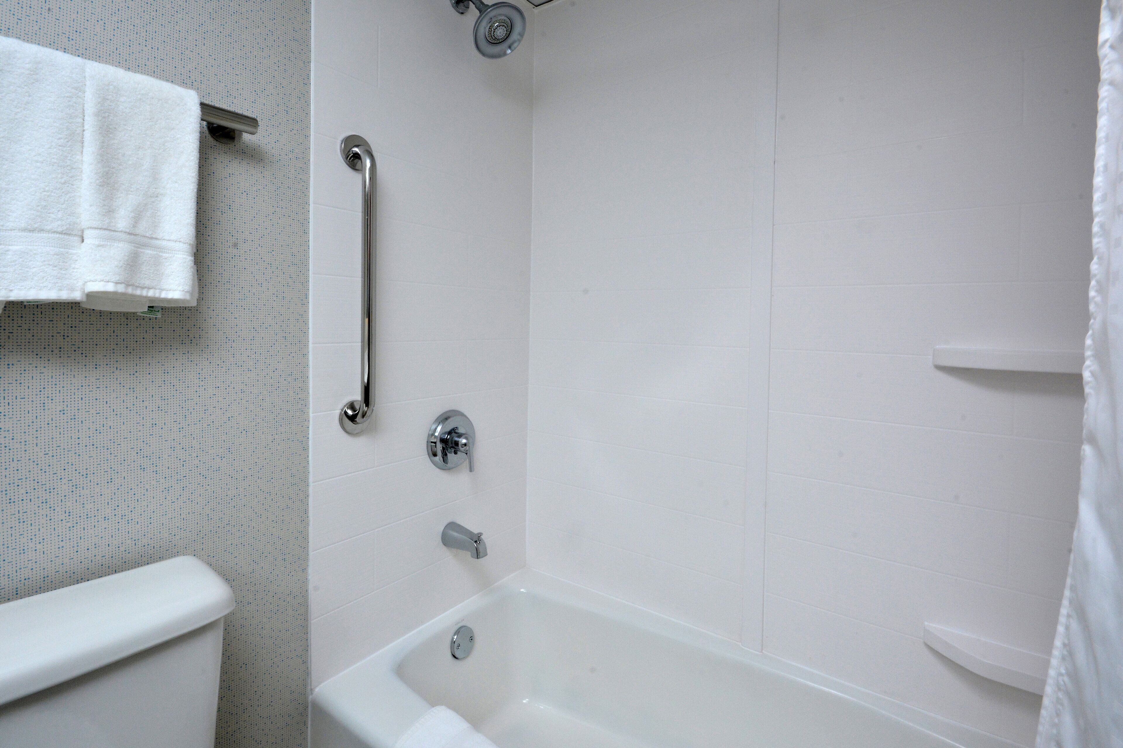 Ein Badezimmer mit einer weißen Badewanne, einer Toilette und einer Haltestange.