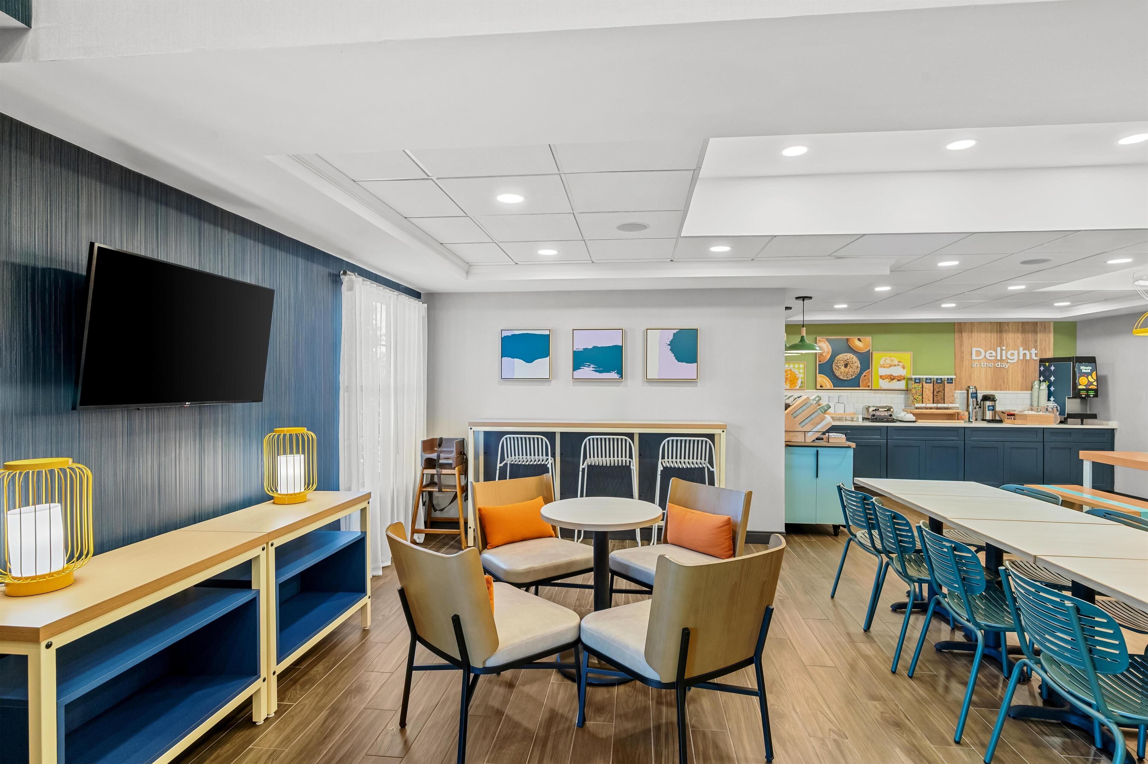 A modern dining area with a long table, chairs, and a television mounted on the wall.